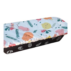May include: A white loaf pan cover with a colorful fruit and vegetable print. The cover features pears, lemons, peas, and strawberries. The cover is made of cotton and is machine washable.