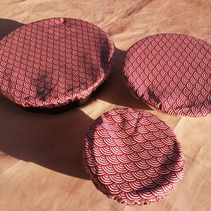 K&ouml;nnte beinhalten: Drei wiederverwendbare Lebensmittel-Abdeckungen in verschiedenen Gr&ouml;&szlig;en mit einem roten und wei&szlig;en Muster. Die Abdeckungen sind aus Stoff und haben ein gewelltes Design.