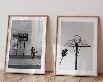 May include: Two black and white framed photographs. The left photo shows two people playing basketball on an outdoor court. The right photo shows a basketball hoop with a palm tree in the background.