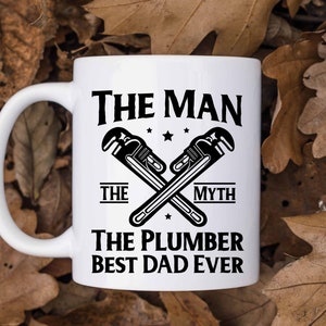 May include: White ceramic mug with a black design. The design features two crossed wrenches with the text "The Man The Myth The Plumber Best Dad Ever".