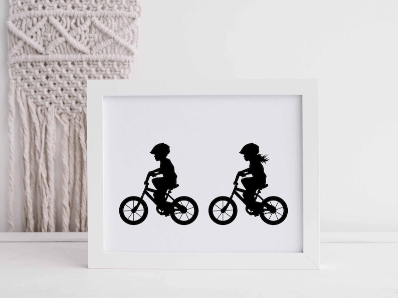 May include: Black and white silhouette print of two children riding bicycles. The print is framed in a white frame.