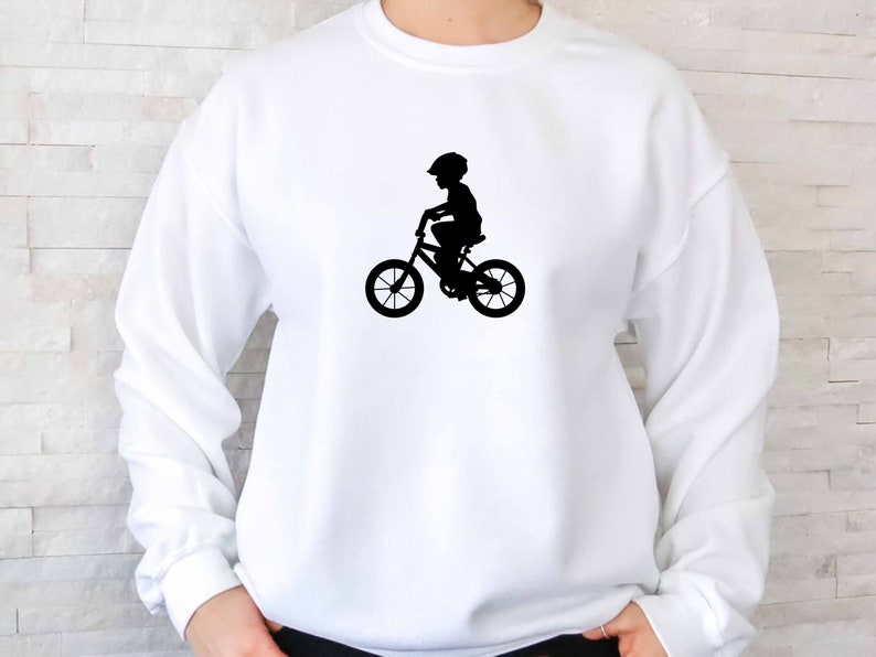 May include: White sweatshirt with a black silhouette of a child riding a bicycle.