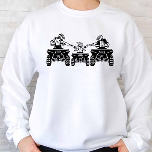 May include: White sweatshirt with a black graphic of three people riding ATVs. The people are holding hands and the ATVs are side by side.