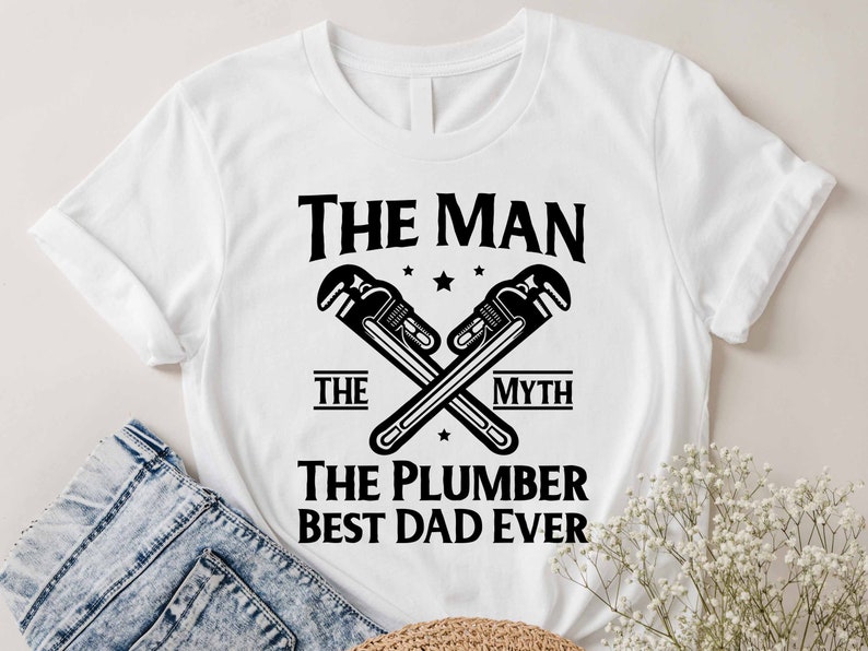May include: White t-shirt with black text that reads "The Man The Myth The Plumber Best Dad Ever". Two crossed wrenches are above the text.