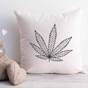 May include: A white pillow with a black outline of a marijuana leaf printed on it.