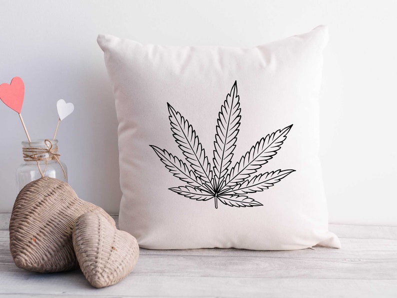 May include: A white pillow with a black outline of a marijuana leaf printed on it.