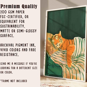 May include: A framed art print featuring an orange tiger resting on a striped pillow and green background. The print has a white border and includes text about the paper quality, ink, and fade resistance.