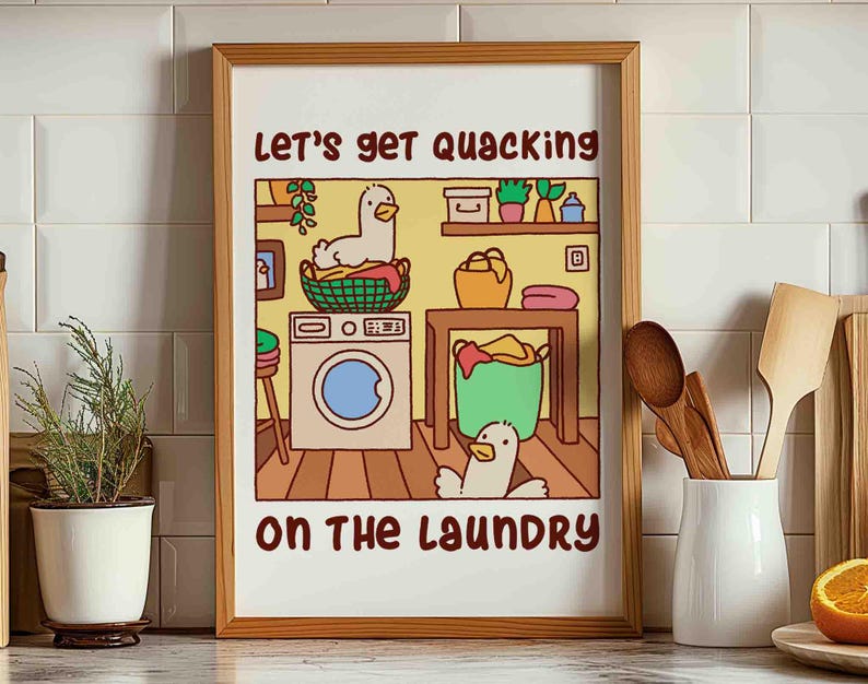 A colorful poster print of two ducks, or goose, doing the laundry. One is sitting in the dirty clothes basket and the other runs around.
