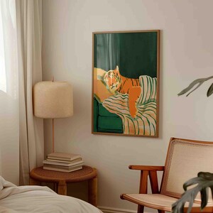 May include: A framed art print featuring a stylized tiger lounging on a green and striped sofa. The tiger is depicted in shades of orange and brown, with a relaxed pose. The artwork has a modern, minimalist aesthetic.