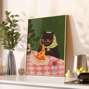 May include: A framed art print depicts a black cat wearing glasses and a scarf, enjoying a slice of pizza at a table with a checkered tablecloth. A bottle of wine and a glass of red wine are also on the table. The artwork has a gold frame.