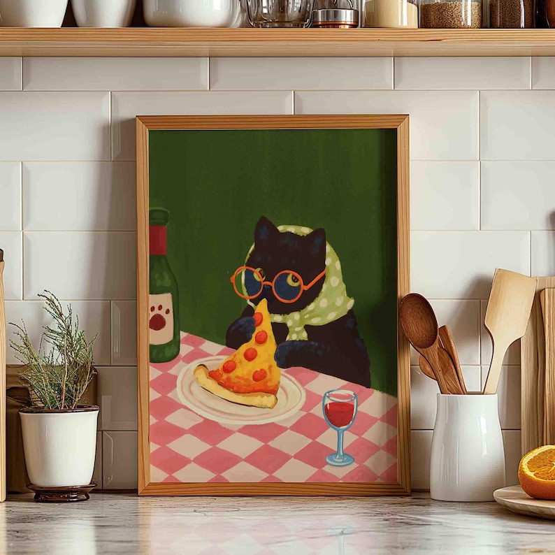 May include: A framed art print depicts a black cat wearing glasses and a scarf, enjoying a slice of pizza and a glass of wine. The cat is seated at a table with a pink and white checkered tablecloth, with a green background.