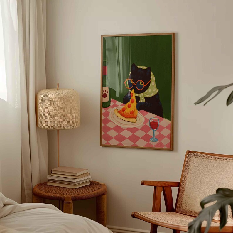 May include: A framed art print depicts a black cat wearing glasses and a scarf, enjoying a slice of pizza and a glass of wine. The cat sits at a table with a red and white checkered tablecloth. A bottle of wine is also on the table.