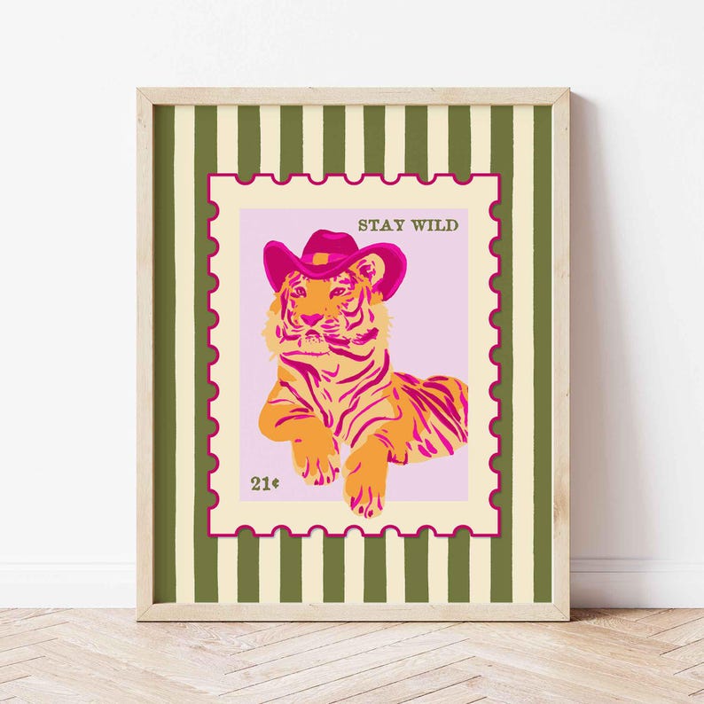 May include: Framed print with a tiger wearing a pink cowboy hat, set on a pink background within a postage stamp design. The text "STAY WILD" is above the tiger, and "21&cent;" is at the bottom. The frame has a green and white striped pattern.