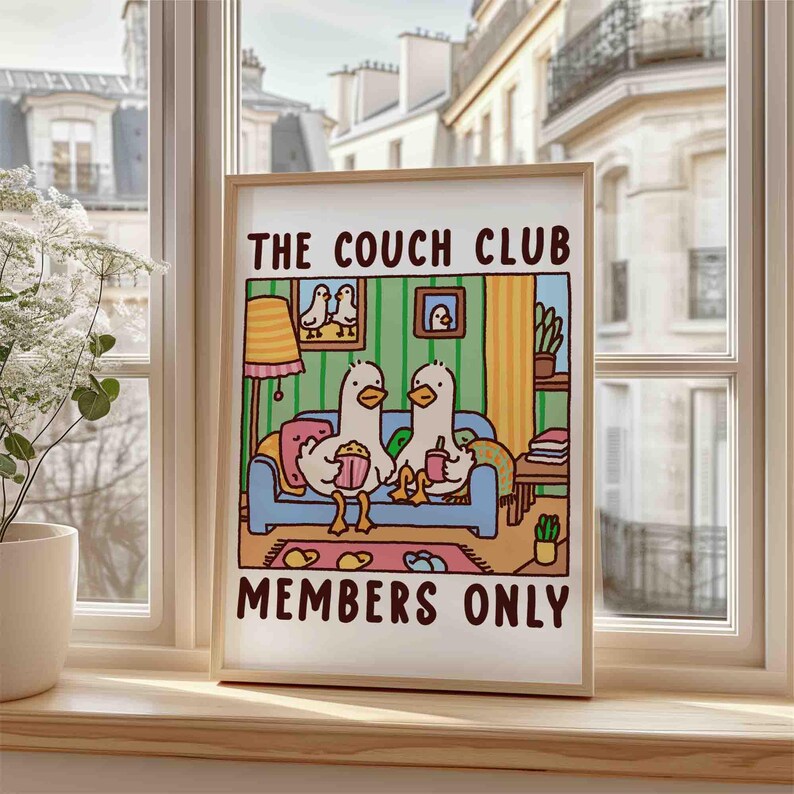 May include: A framed print with a cartoon illustration of two ducks sitting on a couch watching television. The print has the text "The Couch Club Members Only" at the bottom.