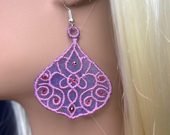 May include: A single, ornate earring with a silver hook. The earring features a lavender-colored, filigree-style design with small, red gemstones. The earring is in the shape of a teardrop or a stylized fan.