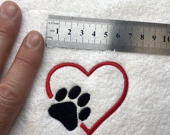 Könnte beinhalten: Weißes Handtuch mit einem roten Herzen und einem schwarzen Pfotenabdruck, der darauf gestickt ist.