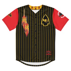 May include: Black baseball jersey with yellow pinstripes and red sleeves. Features a yellow arrowhead logo with "KS" inside, and a design of two feathers. The jersey has a button-up front and a "SMOKE SHOW" logo on the sleeve.