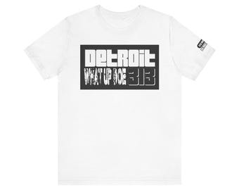 May include: White t-shirt with a black rectangle graphic. The graphic features the word "DETROIT" above "WHAT UP DOE 313" in white, bold, block letters. A small rectangular graphic is on the right sleeve.