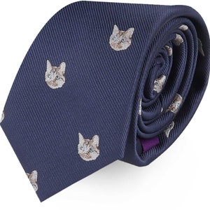 May include: A navy blue silk tie with a repeating pattern of brown and white cat faces.