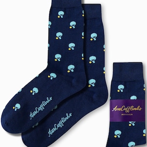 May include: Navy blue socks featuring a repeating pattern of light blue and yellow ping pong ball graphics. The socks are branded with "AusCufflinks Australia". One pair is folded with a purple band.