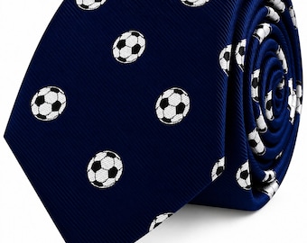 May include: A dark blue necktie featuring a repeating pattern of small, white and black soccer balls. The fabric has a subtle diagonal ribbed texture, and the tie is shown rolled up to display the pattern across the front and side folds.