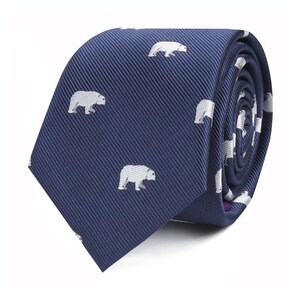 Puede incluir: Corbata azul marino con un patrón repetido de siluetas de osos polares blancos. La corbata está hecha de una tela texturizada y está enrollada, mostrando la continuidad del patrón. Un accesorio elegante para ocasiones formales o informales.