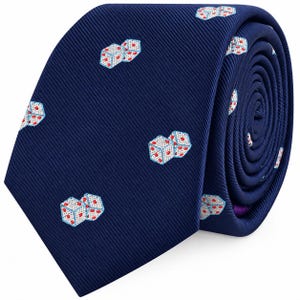 Peut inclure: Une cravate bleu marine ornée d'un motif répétitif de dés blancs avec des points rouges. Le tissu présente une texture subtilement côtelée en diagonale, et la cravate est enroulée pour montrer le motif sur le devant et le côté.