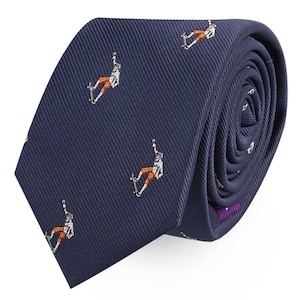 Pode incluir: Gravata azul marinho com um padrão repetido de skatistas em laranja e branco. A gravata é feita de tecido texturizado e está enrolada, mostrando um detalhe roxo nas costas.