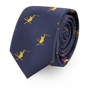 Puede incluir: Una corbata de seda azul marino con un patrón repetido de esquiadores amarillos. La corbata está enrollada y lista para ser usada.