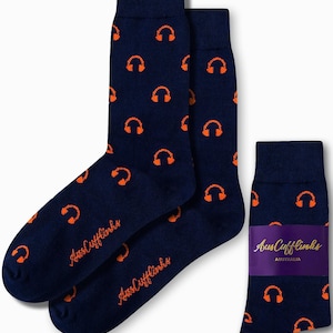 May include: A pair of navy blue socks with an orange headphone pattern. The socks are packaged with a purple and gold label that says "Aus Cufflinks AUSTRALIA".