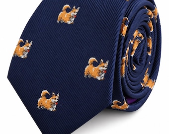 May include: A navy blue necktie featuring a repeating pattern of small, orange and white corgi dogs. The fabric has a diagonal ribbed texture, and the dogs are depicted in a standing position with their tongues visible. The tie is rolled up.