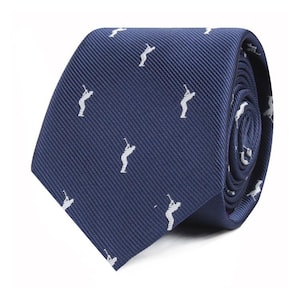 Può includere: Una cravatta blu navy con un motivo ripetuto di figure di golf bianche. La cravatta è realizzata in tessuto a coste ed è parzialmente arrotolata, mostrando il motivo e la trama. Questo accessorio è adatto agli appassionati di golf.