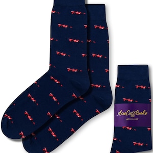 May include: A pair of navy blue socks with a red race car pattern. The socks are packaged with a purple and white label that says "AusCufflinks AUSTRALIA".