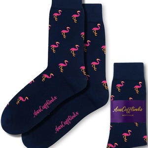 May include: Navy blue socks with a repeating pattern of pink flamingos. The socks have a cuff and the text "AusCufflinks" in pink. A pair of socks is displayed next to a single sock with a purple band.