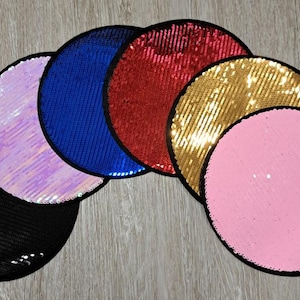 May include: Six round, flat, sequin-covered patches in various colors, including black, iridescent, blue, red, gold, and pink. The patches are arranged in a semi-circle.