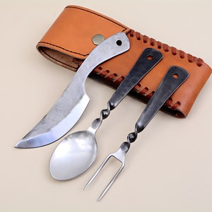Könnte beinhalten: Ein handgefertigtes dreiteiliges Besteckset mit Messer, Löffel und Gabel. Die Utensilien haben eine rustikale, gehämmert Metalloberfläche und gedrehte Griffe. Sie werden mit einer braunen Lederscheide mit Knopfverschluss präsentiert.