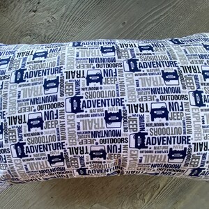 May include: A white pillow with a blue and grey pattern of the words "Adventure", "Trail", "Mountain", "Jeep", "Fun", "Nature", "Outdoors", and "Explorer".