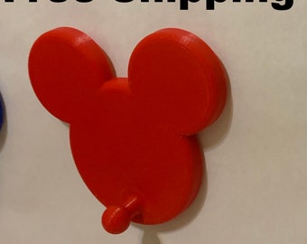 Könnte beinhalten: Roter Mickey Mouse-förmiger Wandhaken aus Kunststoff mit einem einzelnen Haken an der Unterseite. Kostenloser Versand.