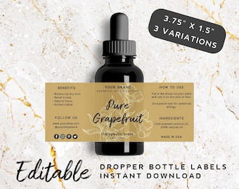 Op de afbeelding: Bewerkbare etiket sjabloon voor een druppelfles van 9,5 cm bij 3,8 cm. Het etiket is goudkleurig met zwarte tekst en heeft een bloemmotief. De tekst op het etiket luidt "Your Brand Essential Oil Collection Pure Grapefruit Therapeutic Grade 10ml 125".