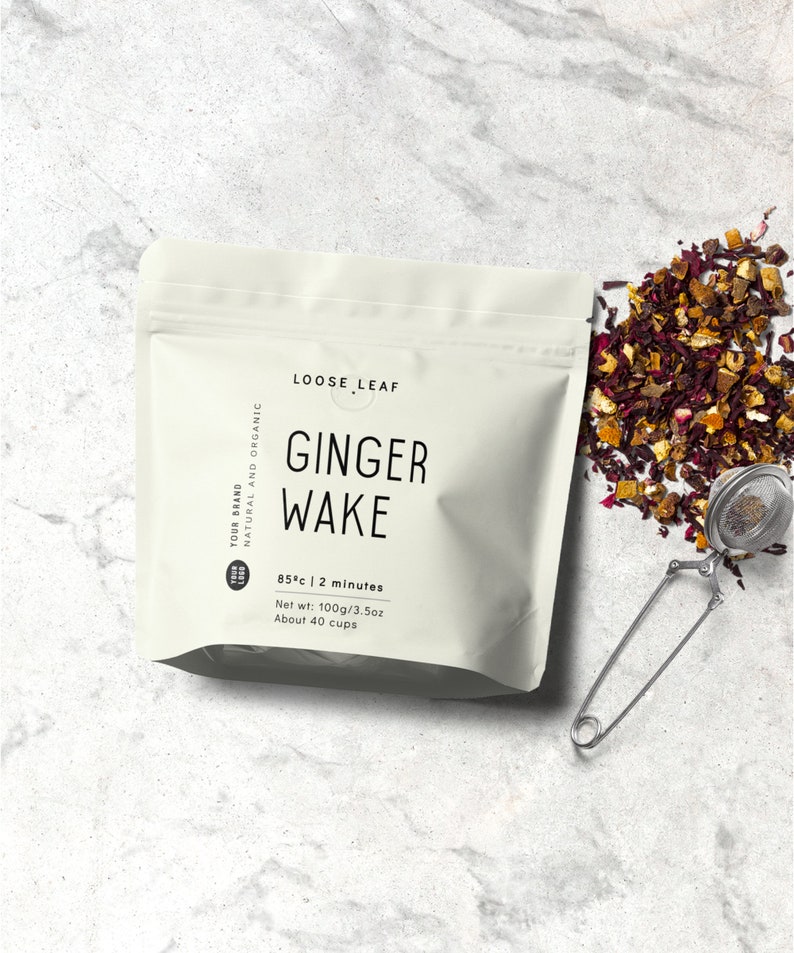 Op de afbeelding: Een witte zak met de tekst "LOOSE LEAF GINGER WAKE" erop gedrukt. De zak bevat losse thee en heeft instructies voor het zetten: 85 &deg;C | 2 minuten. Nettogewicht: 100 g/3,5 oz. Ongeveer 40 kopjes.