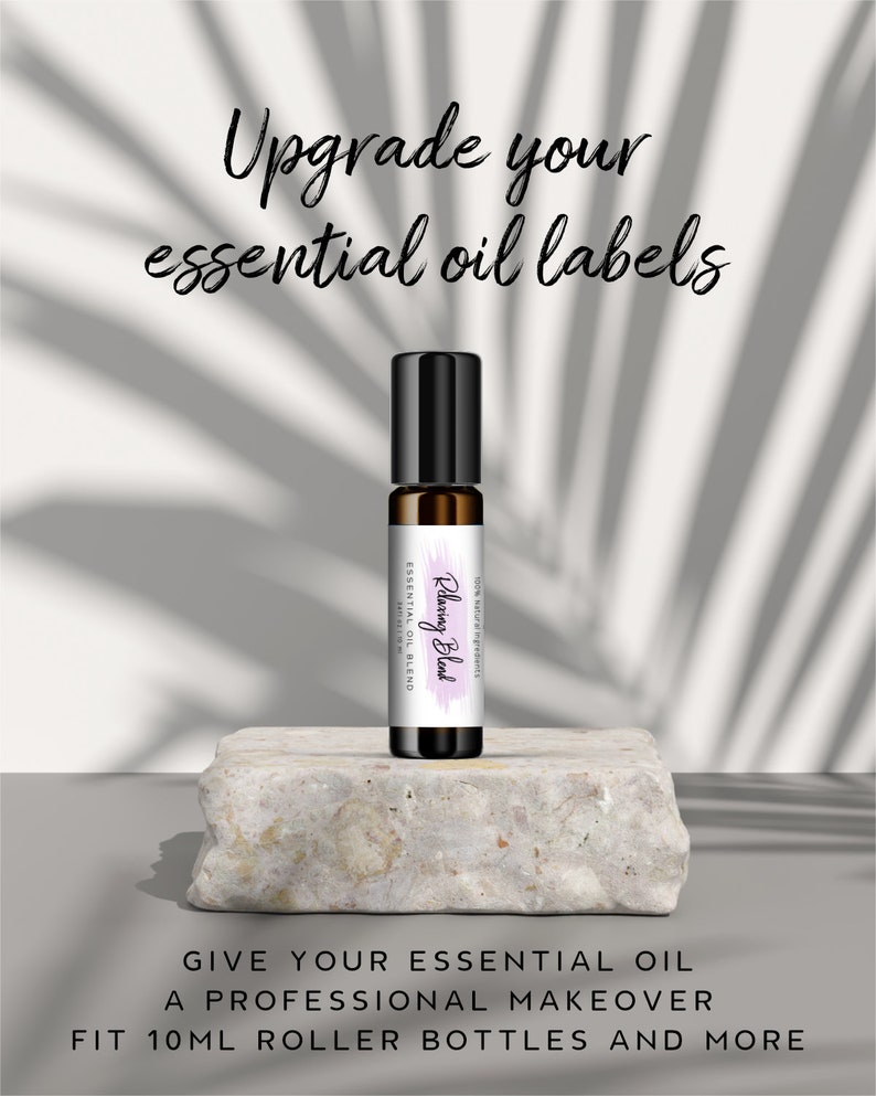 May include: A close-up of a 10 ml roller bottle with a white label that says "Rejuvenating Blend" in purple script. The bottle is sitting on a light gray stone surface. The text "Upgrade your essential oil labels" is at the top of the image. The text "Give your essential oil a professional makeover. Fit 10 ml roller bottles and more" is at the bottom of the image.