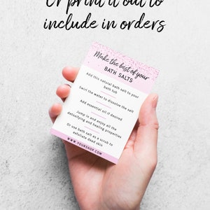 May include: A pink and white card with instructions on how to use bath salts. The card says "Make the best of your bath salts" and includes steps like adding the salt to the bath tub, swirling the water to dissolve the salt, and adding essential oil. The card also says "Jump in and enjoy all the detoxifying and healing properties" and "Or use bath salt as a scrub to exfoliate dead skin." The card ends with the website address "www.yourshop.com".