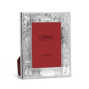 May include: A silver picture frame with an ornate design. The frame is made by Cunill, Barcelona 1918. It is made of sterling silver 925 and is 8.76 cm tall.