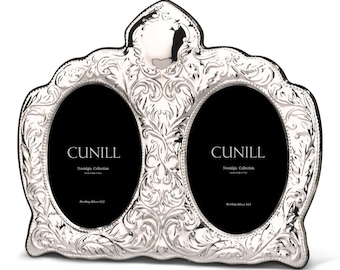 May include: A silver double oval picture frame with an ornate design. The frame has two openings for photos and the words "CUNILL Nostalgia Collection Sterling Silver 925" are printed on the bottom of each opening.