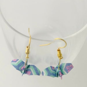 May include: A pair of origami crane earrings with a blue, green, and pink patterned design. The earrings are made with gold-colored hooks.