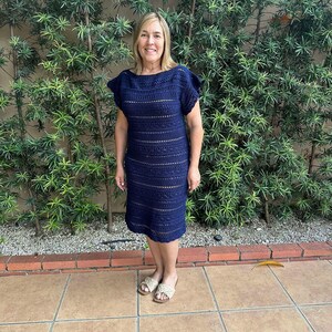 May include: A navy blue crochet dress with a loose fit and short sleeves. The dress has a simple design with horizontal stripes and a slightly flared skirt.