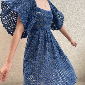 May include: A blue crochet dress with a square neckline and short, ruffled sleeves. The dress has a fitted bodice and a flowing skirt.