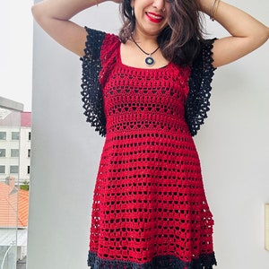 May include: A red crochet dress with black lace trim and short sleeves. The dress has a square neckline and a fitted bodice. The skirt is flared and falls to the knees.