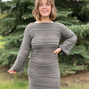May include: A grey crochet dress with long sleeves and a slightly flared skirt. The dress has a textured pattern and a loose fit.