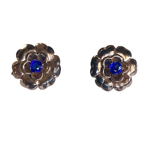 May include: A pair of gold-tone flower-shaped earrings with blue gemstone centers.